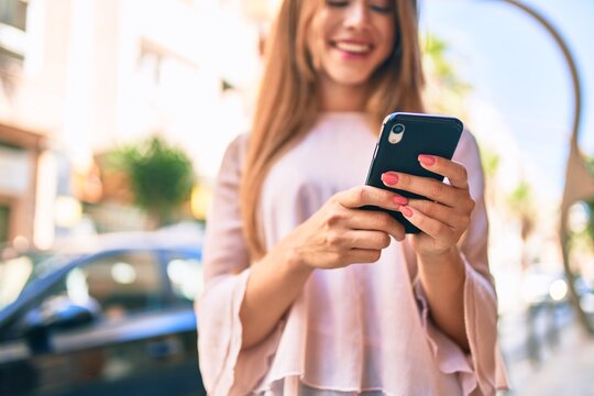 Young caucasian girl smiling happy using smartphone at the city.