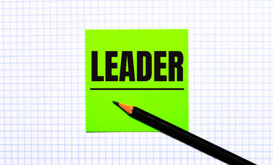 There is a green sticker with the text LEADER and a black pencil on the checkered paper.