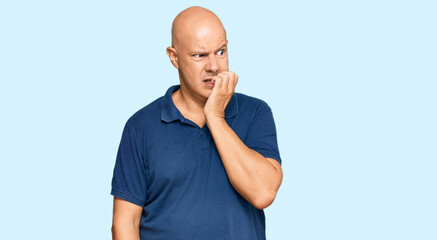 Middle age bald man wearing casual clothes looking stressed and nervous with hands on mouth biting...