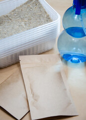 Kit for growing microgreens at home: linen substrate, seeds in package, water spray and plastic bowls with lids. Close up packaging with microgreen seeds with copy space. Home garden concept.