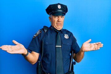 Handsome middle age mature man wearing police uniform clueless and confused with open arms, no idea concept.