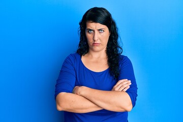 Plus size brunette woman wearing casual blue shirt skeptic and nervous, disapproving expression on face with crossed arms. negative person.