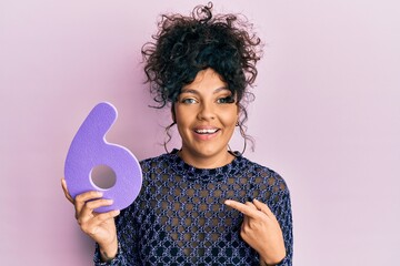 Young hispanic woman holding number six smiling happy pointing with hand and finger