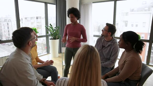 Diverse group of people sitting in circle in group therapy session.