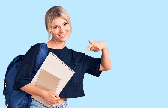 Young beautiful blonde woman wearing student backpack holding notebook pointing finger to one self smiling happy and proud