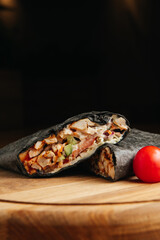 Juicy grilled black shawarma on a wooden board with vegetables and spices meat. Black doner kebab