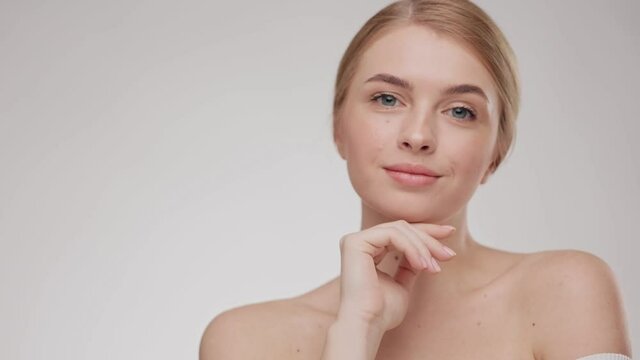 Female look at the camera and smiling. Beauty. Woman model with fresh skin, white smile and natural facial makeup portrait on light background. Close up portrait young beautiful blonde girl.