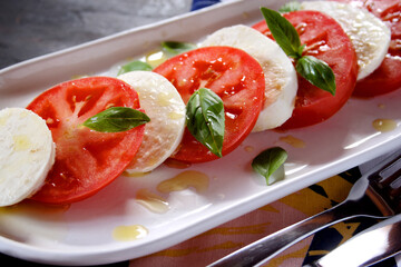 Caprese salad with ripe tomatoes and mozzarella cheese, with fresh basil leaves and olive oil
