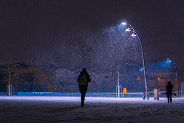 Snow flurries on a square in the evening, street lights and snow flurries, it snows in the evening...