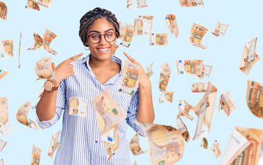 Young african american woman with braids wearing casual clothes and glasses smiling cheerful showing and pointing with fingers teeth and mouth. dental health concept.