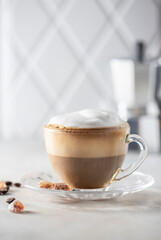 Transparent cup of cappuccino with foam on a white background. Hot latte or cappuccino.