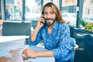 Young middle eastern man talking on the smartphone at coffee shop.