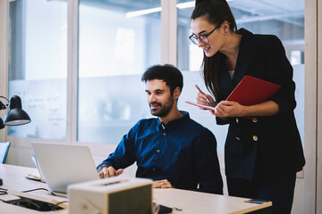 Coworkers browsing laptop while working in office