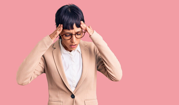 Young brunette woman with short hair wearing business jacket and glasses with hand on head for pain in head because stress. suffering migraine.