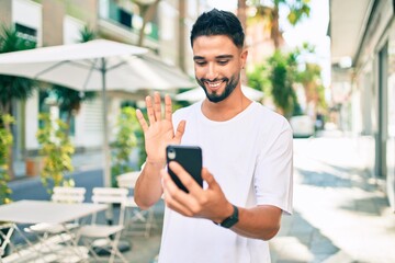 Young arab man smiling happy doing video call using smartphone at the city.