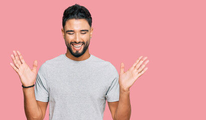 Fototapeta premium Young man with beard wearing casual grey tshirt celebrating mad and crazy for success with arms raised and closed eyes screaming excited. winner concept