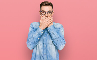 Young redhead man wearing casual denim shirt shocked covering mouth with hands for mistake. secret concept.