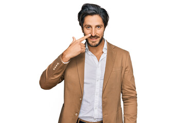 Young hispanic man wearing business clothes pointing with hand finger to face and nose, smiling cheerful. beauty concept