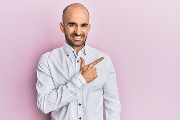 Young hispanic man wearing casual clothes cheerful with a smile of face pointing with hand and finger up to the side with happy and natural expression on face