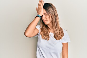 Brunette young woman wearing casual white t shirt surprised with hand on head for mistake, remember error. forgot, bad memory concept.