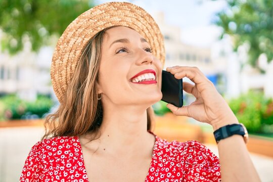 Young blonde woman on vacation smiling happy talking on the smartphone at street of city
