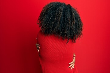 Beautiful african american woman with afro hair wearing sweater and glasses hugging oneself happy...