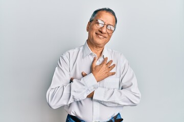 Middle age indian man wearing casual clothes and glasses smiling with hands on chest with closed eyes and grateful gesture on face. health concept.