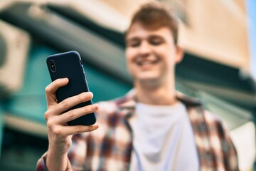 Young caucasian man smiling happy using smartphone at the city.