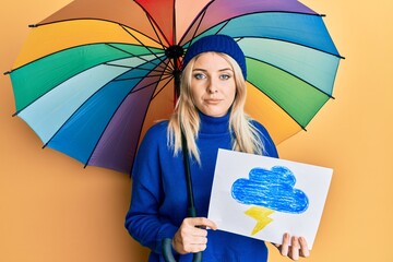 Young caucasian woman holding rain draw and umbrella depressed and worry for distress, crying angry...