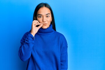 Young asian woman wearing casual winter sweater mouth and lips shut as zip with fingers. secret and...