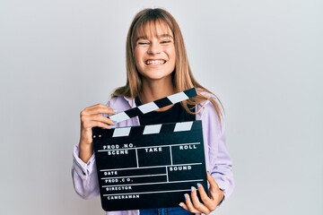 Teenager caucasian girl holding video film clapboard smiling and laughing hard out loud because...