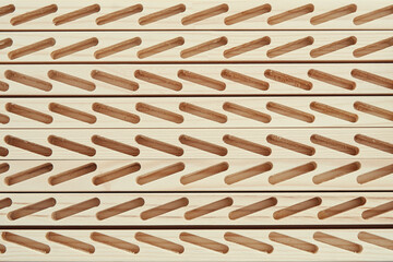 Set of wooden bars with lines of cut slots to install planks for blinds in light carpentry workshop close view from above