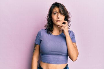 Young hispanic woman wearing casual clothes thinking concentrated about doubt with finger on chin...