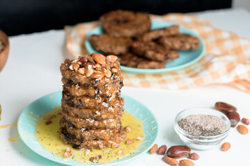 homemade oatmeal banana pancakes with chia seeds, almonds, prunes and dates, drizzled with honey and crushed nuts on a dark background. diet breakfast is healthy for the figure . close-up