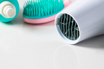 Essential accessories for hair care  and styling, Ionic hairdryer , desired brush and styling spray, in pink mint tone on white background. Modern hairstyling concept.
