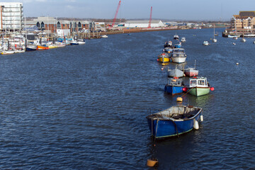Small boats moored on the River Adur pontoons and at anchor in the middle of the river at high tide.