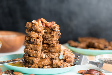 homemade oatmeal banana pancakes with chia seeds, almonds, prunes and dates, drizzled with honey and crushed nuts on a dark background. diet breakfast is healthy for the figure . close-up