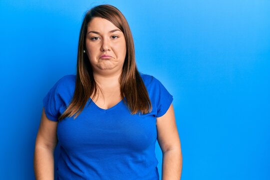 Beautiful brunette plus size woman wearing casual blue t shirt depressed and worry for distress, crying angry and afraid. sad expression.