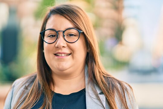 Young hispanic plus size businesswoman smiling happy standing at the city.