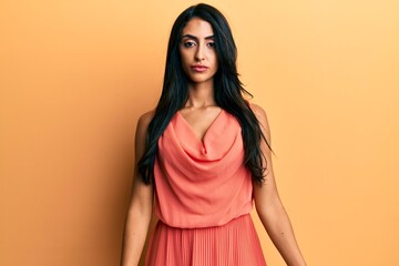 Obraz premium Beautiful hispanic woman wearing summer dress with serious expression on face. simple and natural looking at the camera.