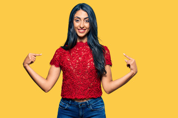 Beautiful hispanic woman wearing elegant shirt looking confident with smile on face, pointing oneself with fingers proud and happy.