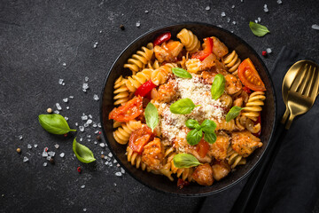 Pasta chicken with tomato sauce. Top view at black table.
