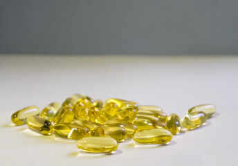 Yellow capsules are scattered on a light background.Soft focus.