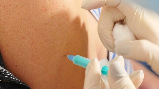 Doctor makes vaccination into female shoulder. nurse injects Covid-19 vaccine against virus. Medical Injection. Doctor vaccinating woman patient. Process of immunization. 4 k video