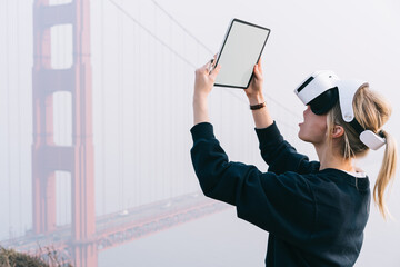 Woman using tablet and VR glasses in USA near foggy Golden Gate