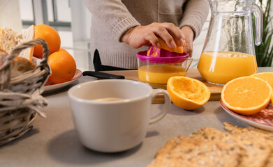 Obraz na płótnie Canvas Woman preparing fresh orange juice in kitchen for breakfast