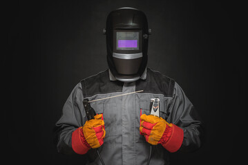 Welder man in the helmet with a welding terminals on the black background.