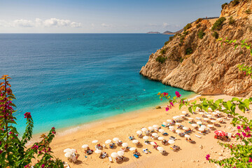 Naklejka premium Kaputas beach with blue water on the coast of Antalya region in Turkey with sun umbrellas on the beach
