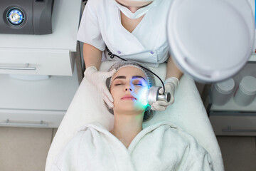 Naklejka premium Ultrasonic massager. Light skin treatment, the woman in the beauty salon