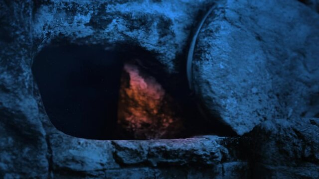Empty tomb of Jesus with candle flickering light from inside.